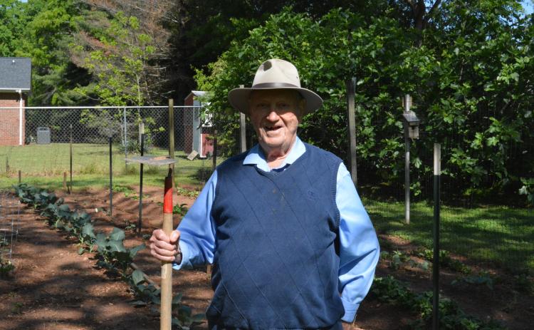 Drew Dotson/The Hartwell Sun - Milner poses with his trusty hoe in front of his backyard garden.