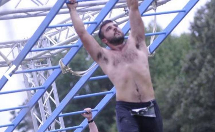 Buchanan traverses the monkey bars on an obstacle course.