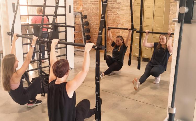 Physique Boutique employee (L-R) MattiGrace, Ashley Barry, Miyana Vaca and Lauren Lee demonstrate techniques on the gym's suspension bars.