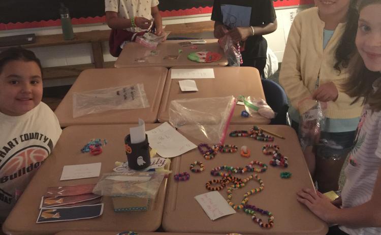 From left to right, students Allie Martinez-Johnson, Jaylen Perez-Rangel, Amonzo Gantt, Maria Benites, and Anna Holmes set up their booths for the Economics Fair at South Hart Elementary School.