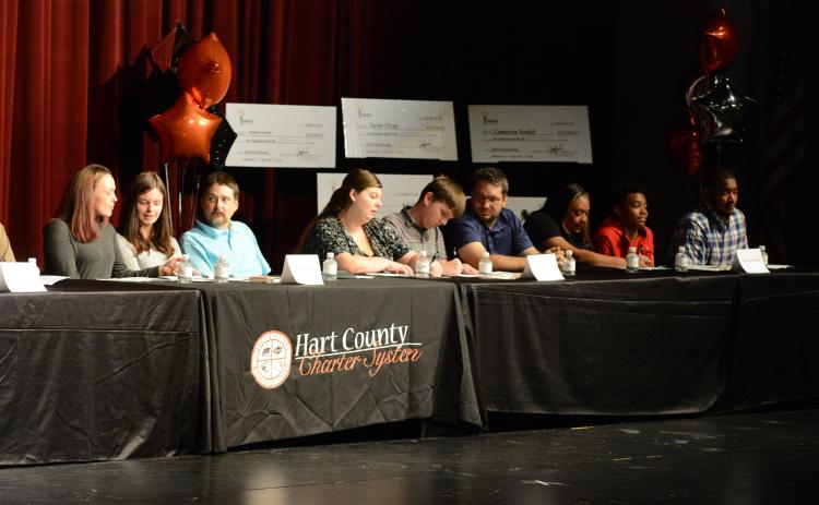 Drew Dotson/The Hartwell Sun From left to right, students Taylor Floyd, Joshua Vaughn and Camarion Verdell sign their scholarships as their proud families look on.