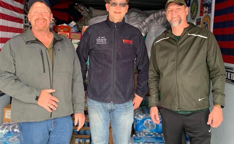 Patrick Wireman (left), a VFW volunteer (center), and Jason Nichols (right) help load supplies in Wireman’s trailer for tornado victims in Ky.