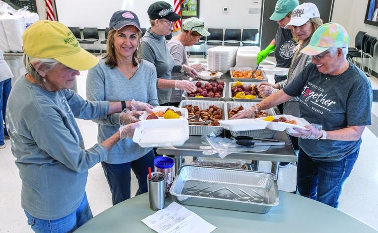 Kate Kirby, Brigid Richardson, Marylynn Johnson prepare plates for drive-through customers.