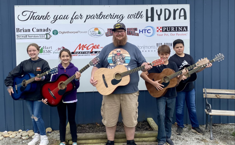 Kids learn guitar alongside their instructor at HYDRA event.