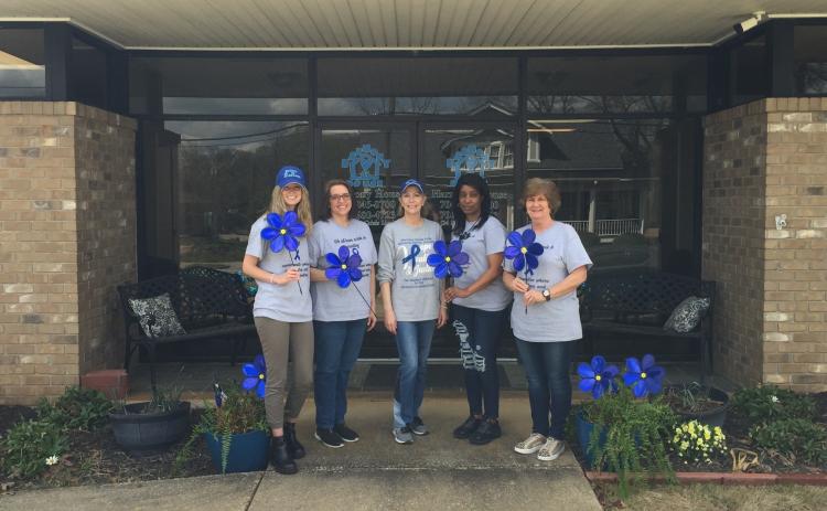 From left to right, Andrea Ploussard, Wendy Risner, Laurie Whitworth (CEO), Kimberely Brewer and Sydney Jordan stand outside Harmony House holding blue pinwheels, which is the national symbol for child abuse prevention month. The pinwheel connotes playfulness, joy, and childhood.