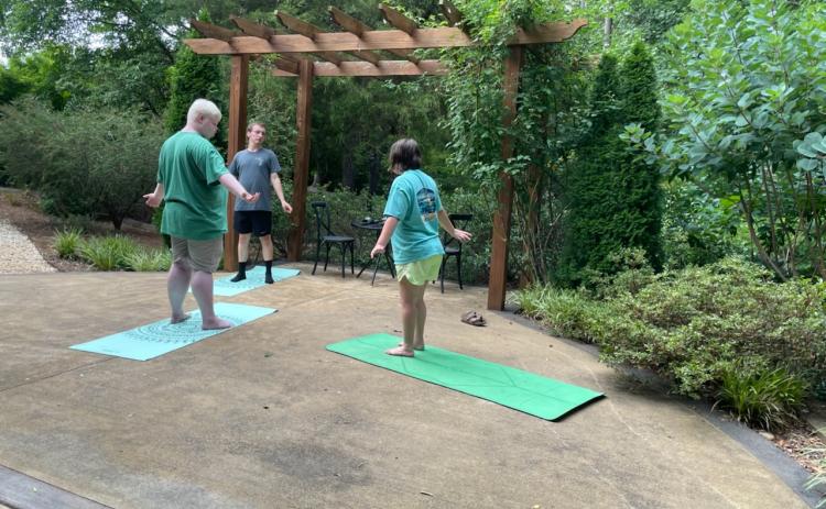 Yoga instructor Briana Kay (right) leads Jake Mitchell (left) and Justin Temples (center) in a yoga session at the Hart County Botanical Garden pavillion.