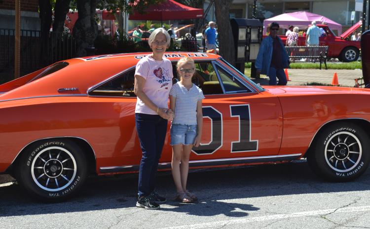 Dan Hunt/The Hartwell Sun - Sue Ackerman and her niece Emmeline Stith pose outside of the Post Office with a 1969 Dodge Charger made up to look like the famed General Lee from the Dukes of Hazzard.