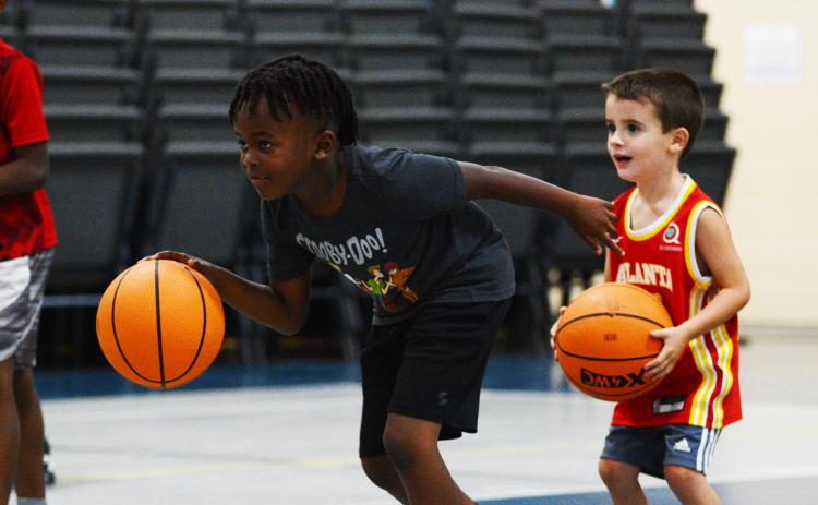 Corbyn White (left) and Korbin Cawthon, the youngest camper, work on their dribbling skills in a game of red light, green light.