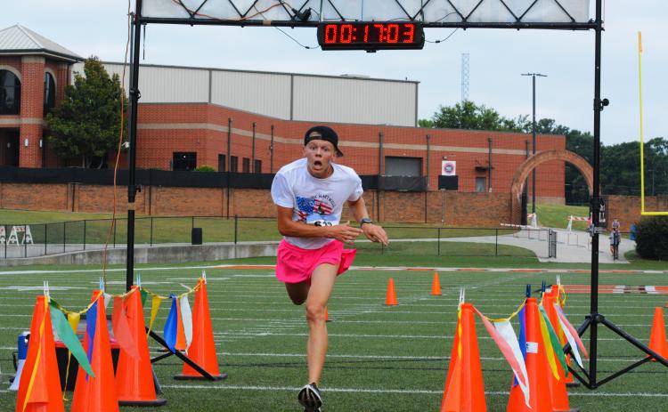 Zachery Benner stumbles past the finish line to finish first overall in the Historic Hartwell 5K on June 2.