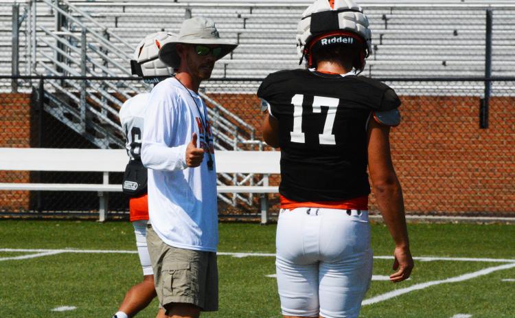 Caleb Sorrells coaches up quarterback Austen Whitworth at practice.
