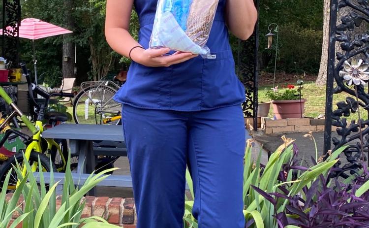 Nurse Cassie Gowder holds up her COVID protective gear she wore at work to help protect her patients.
