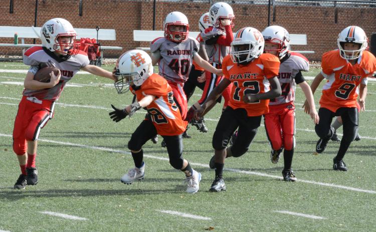 Hart County 7U running back Tristan Gray throws a stiff arm with defender Emmett Wise bearing down.