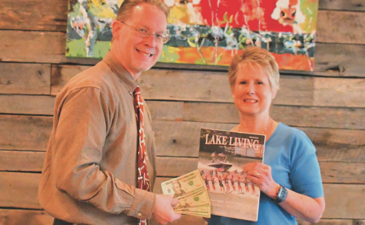 Enoch Autry, publisher for The Clayton Tribune in Rabun County, presents the $100 prize to Rabun County resident Melissa Elzey for winning the Spring 2023 Lake Living cover contest with her capture of the Lake Burton Ski Patriots’ performance on July 4, 2021.