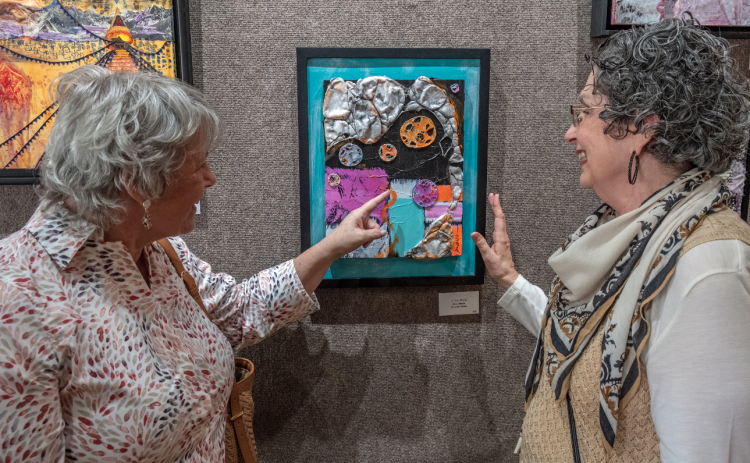 Above, (L-R) Lynn Smith and Diana Walter discuss Diana’s art during the Hartwell Art Center’s opening reception for ‘Awakenings’ May 5. Below, art patrons view the artwork in the show.
