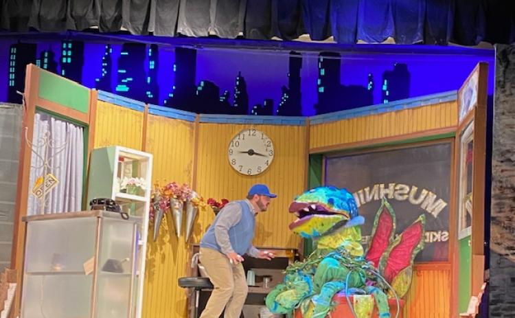 Actor Ethan Smith as Seymour speaks to Audrey II controlled by puppeteer Elna Brynestad.