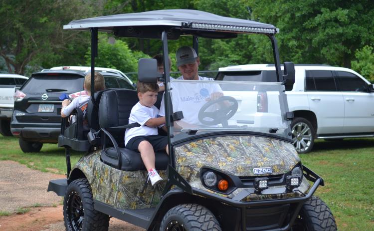 Jackson Moon and his father Zachary riding in their brand new golf cart from the Make-A-Wish Foundation.