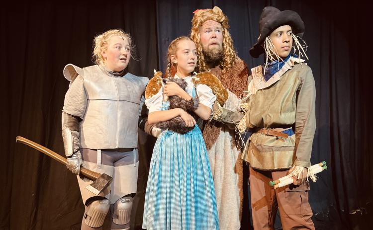 The Ruby Cast during rehearsals for The Wizard of Oz. Pictured from left to right is Morgan Haymes as the Tin Man, Lainey Dickson as Dorothy, Seth Howard as the Cowardly Lion, and August Thompson as the Scarecrow.