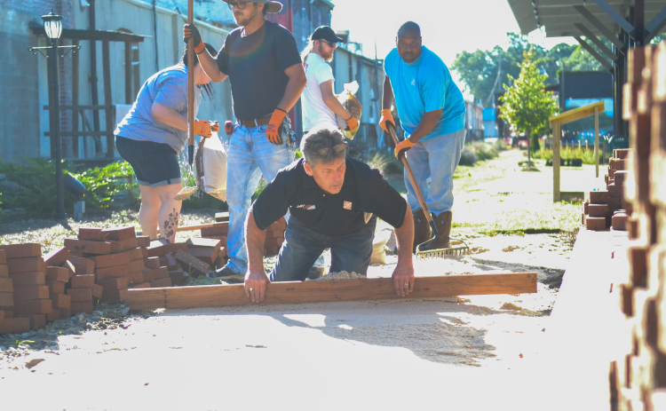 Hartwell Home Depot manager Jeff Meitz (center left) and staff members Katherine Alewine, Jennifer Hill, Angela Zimmerman, Gavin Dutton, Chris Parr, Zack Mattox, Teresa Hoover, and Britt Dyar help  to repair an uneven brick walkway at Railroad Street Park.