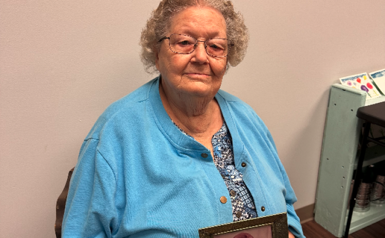 Frances Bailey holding an older photo of herself.