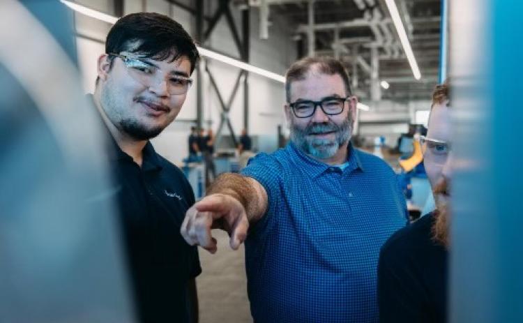 Haering Precision`s Academy Manager Tim Bennett (center) working with machining apprentices.