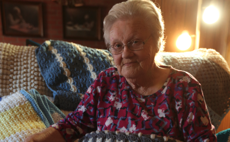 Beverly White sits in her home in the Cross Roads community surrounded by dozens of the brightly colored blankets she’s crocheted over the years after learning the skill from a customer in Jim’s Grill in the early 80s. Right, Beverly sits with her favorite blanket featuring the “Kittens in a Row” pattern.