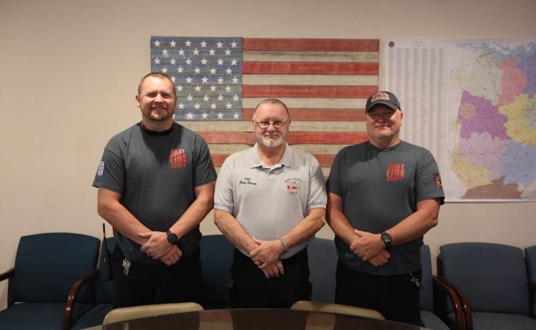 Hart County firefighters (L-R) Matt Evans, a firefighter and paramedic, Chief Jerry Byrum and Teddy Gibson, a firefighter and EMT, stand in front of a flag they made out old firehoses inside the Hart County Fire Department administration office. (Photo/Rose Scoggins)