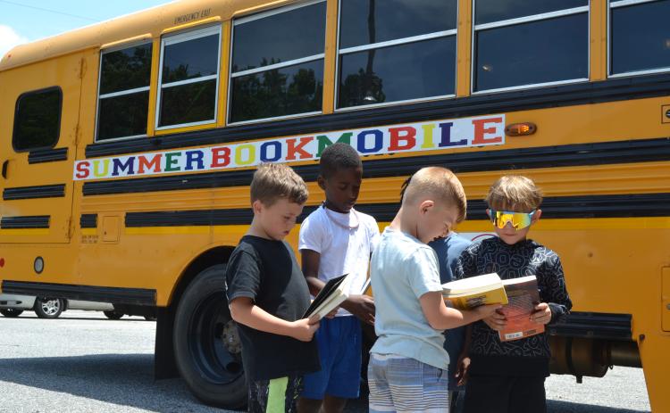 Children at the Hart Youth Development Resource Association (HYDRA) show off their books to each other outside the Hart Partners Bookmobile on Tuesday. The Bookmobile provides free snack bags and books for all children age groups, from toddlers to teenagers, throughout Hart County. (Photo/Adriana Cascio)