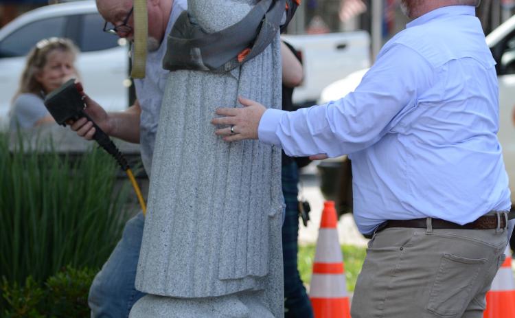 Hartwell Economic and Community Development Director Jason Ford (right) helps hold the statue in place as Mart Clamp helps adhere the statue to its pedestal (left). (Photo/Benjamin London)