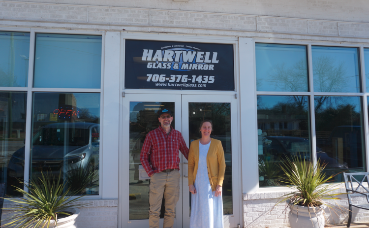 Lyle (left) and Margaret (right) Koehn standing in front of their business, Hartwell Glass and Mirror. The shop is turning 30 this year. Photo by Madison Linton.