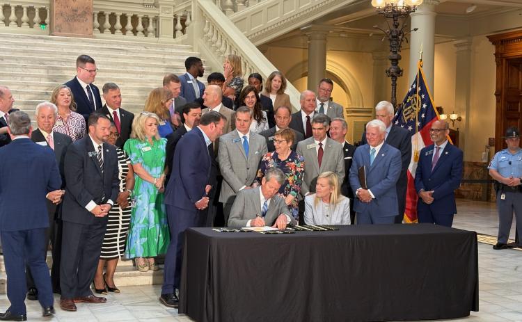 Gov. Brian Kemp selects a pen to sign tax legislation at the Georgia Capitol in Atlanta on Monday, with wife Marty by his side. House Speaker Jon Burns, R-Newington, watches to her left. Photo by Ty Tagami.