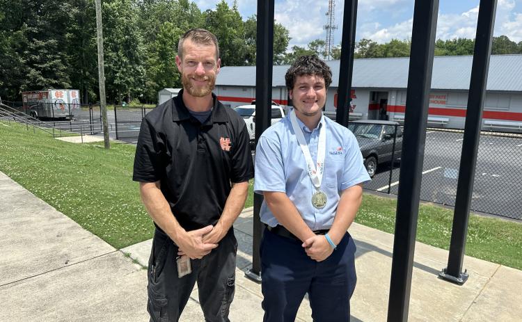 Jimmy Reynolds (right) poses for a photo with Marine Engine Technology instructor Tyler Floyd (left) after ringing the Victory Bell at Hart County High School following his National Championship win. Photo by Grayson Williams.