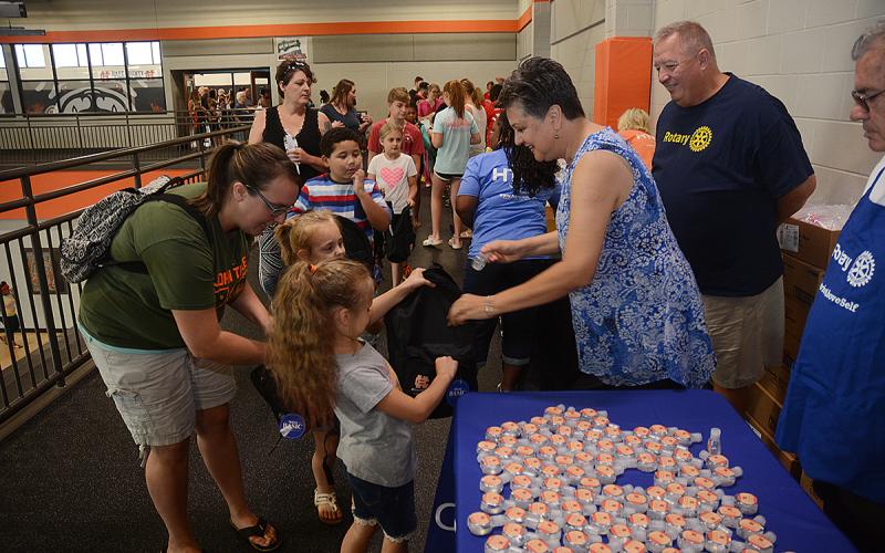 Hartwell Rotary Club member Ganine Derleth gives hand sanitizer to Elektra Head, 7, and her sister Ziva Head, 5, while their mother Kimberly Head helps and club member Mike Everett, standing at right, looks on.