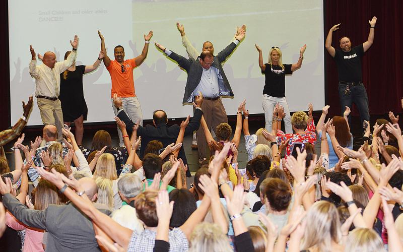 Ed Nichols, in the center of the stage, leads Hart County Charter System faculty and staff in a group YMCA dance. 