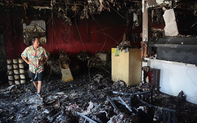 Sunshot by Michael Hall — Little Japan co-owner Tommy Vang walks through the dining room and past the sushi bar at the restaurant on Tuesday as insurance adjusters assess the damages from an Aug. 2 fire.