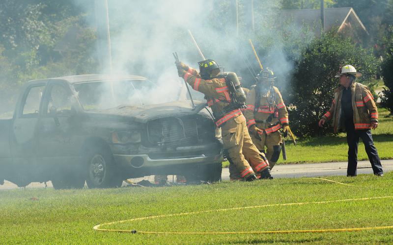 Sunshot by Michael Hall — Hartwell firefighters pry open the hood of a Dodge Ram that burst into flames Thursday in the parking lot of the old Bells Shopping Center. 