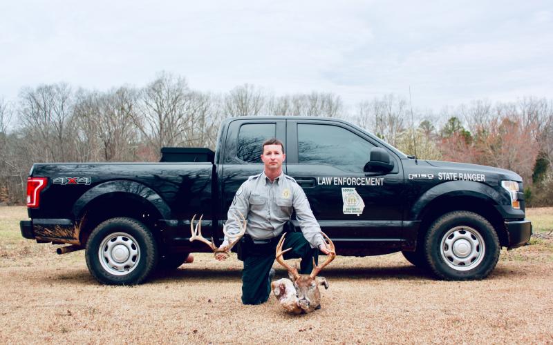 Sunshot by Grayson Williams — DNR Cpl. Craig Fulghum poses for a photo with a deer that was killed illegally.