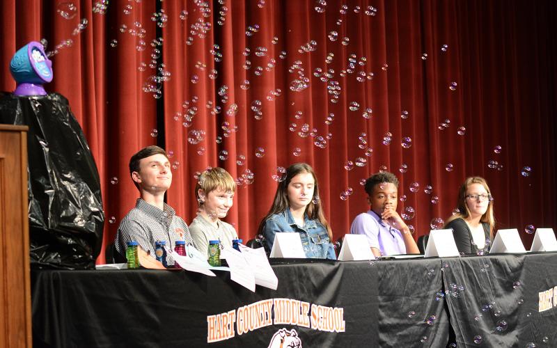 Sunshot by Michael Hall — The 2019 class of REACH Scholars, from left to right, Mason Carey, Ethan Cleveland, Emily Evans, Jashon Gaines and Trinity Wilson, watch bubbles fly as keynote speaker Dink NeSmith, Community Newspapers Inc. president, makes a point about dreams needing to be protected like soap bubbles floating in the wind past jagged rocks.