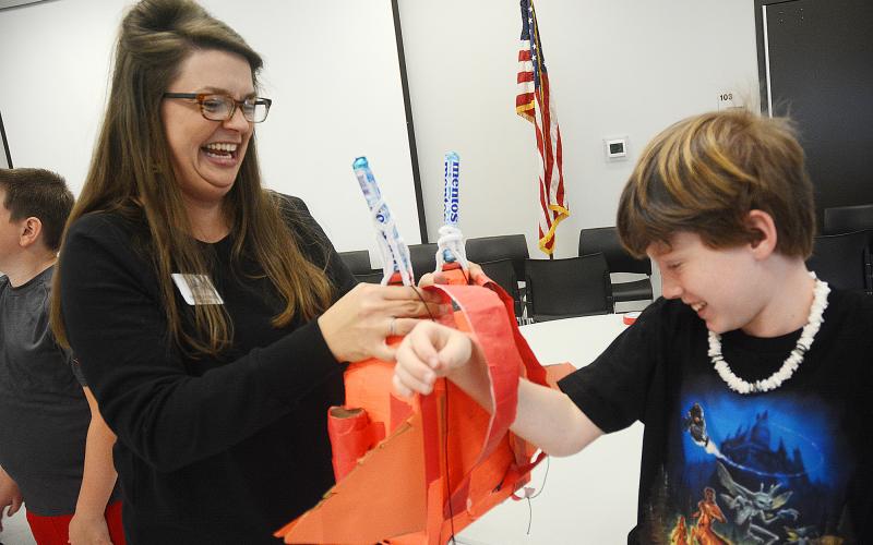 Sunshot by Michael Hall — North Hart Elementary School Teacher of the Year Emilee Patrick helps Ryan Belanger put a jetpack he invented on his back during the recent Invention Convention at the Agriscience Center. 