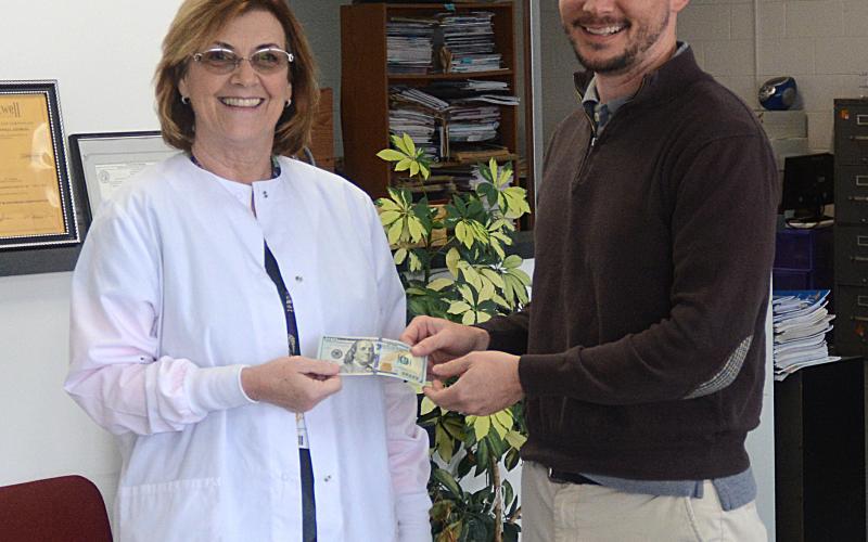 Elaine Jones, left, receives her $100 reward for winning the Lake Living winter cover contest from The Hartwell Sun publisher Michael Hall.