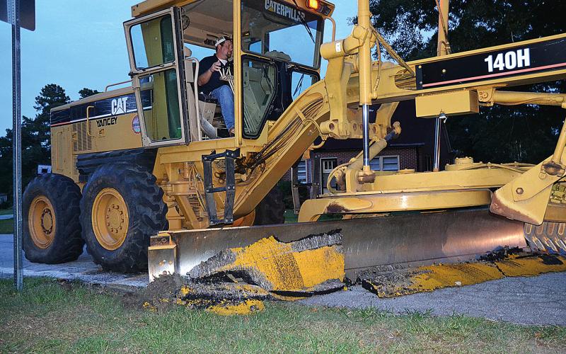 A Hart County road crew employee removes the speed bumps in Bowersville in August.