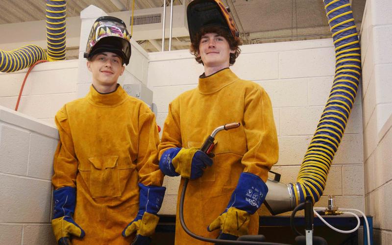 Sunshot by Michael Hall — Hart College and Career Academy students Zack Hart, left, and Austin Brown, right, pose for a photo in the welding lab at the school recently.  The pair were hired recently to work at Fabritex in Hartwell. 