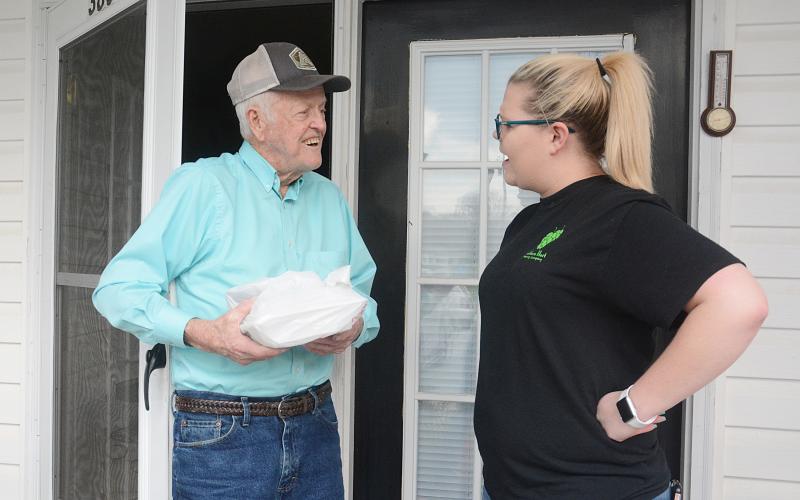 Sunshot by Michael Hall — Dan Powell, 90, left, accepts a free meal from Southern Hart Brewing Co. employee Emily Reynolds last Thursday in Hartwell.