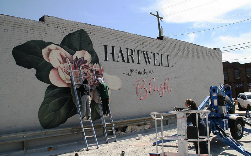 University of Georgia art students Katie Eidson, Alondra Arevalo and Rina Yoo work on a mural on the side of Blush Hair Studio in downtown Hartwell.