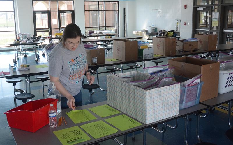 Sunshot by Michael Hall — Andi Swann, a paraprofessional at North Hart Elementary, looks for supplies to give to a family who drove through the parking lot at the school on Friday to pick up learning materials for home learning.