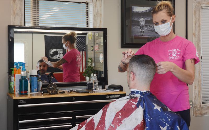 Sunshot by Michael Hall — Beards and Shears Barbershop owner, Julie Thomas, cuts the hair of Clint Bridges last Friday, April 24, on the first day she was allowed to open again following a closure due to the COVID-19 pandemic.