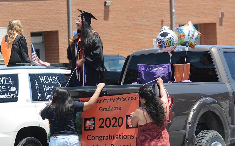 Sunshots by Michael Hall Maria Rangel talks with another graduate as her family helps her hang a banner from the back of a truck prior to the Parade of Graduates on May 23 in Hartwell. 