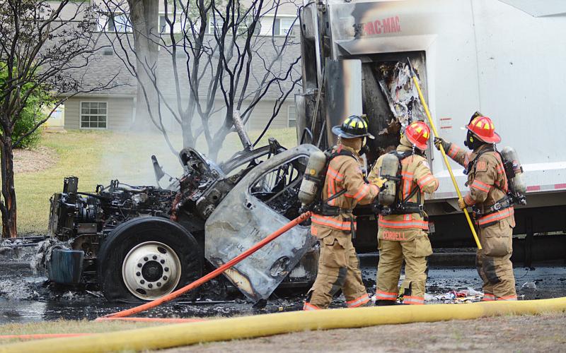 Sunshot by Michael Hall — Hartwell firefighters check to make sure the there is no fire in the cargo area of the garbage truck that caught fire Thursday at Woodlake Apartments.