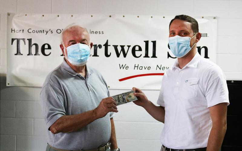 Sunshot by Grayson Williams — Photographer Bill Powell, left, accepts the $100 prize for winning the Summer Lake Living cover photo contest from The Hartwell Sun publisher Michael Hall. 