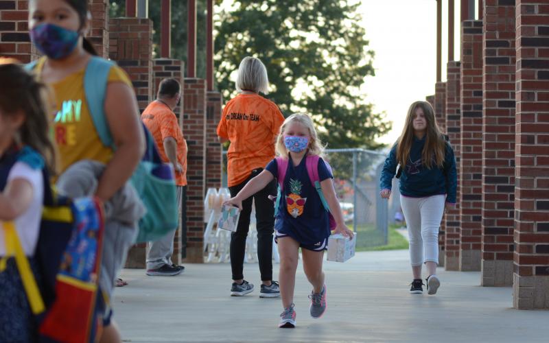 Sunshot by Michael Hall — Danica Kerr, middle, a first-grade student at Hartwell Elementary, runs to class after being dropped off at the school on Monday, Aug. 17 for the first day of the 2020-2021 academic year.