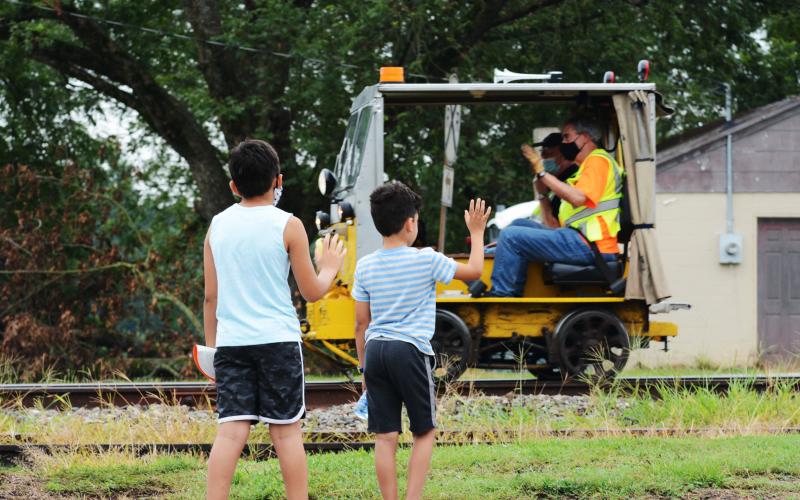 Children who came as spectators to see the railcars wave at a passing car as the journey begins. 